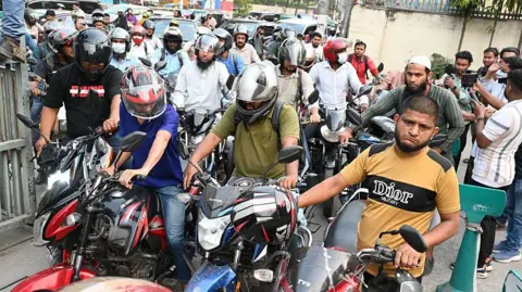 Getty Images Motorcyclists packed in a long queue a petrol station in Bangladesh