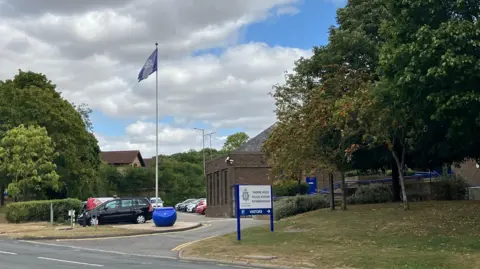 Thorpe Wood police station, with a white board with a blue "Thorpe Wood" sign and a blue flag