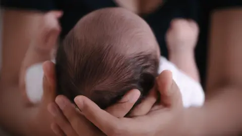Baby cradled in arms of mother