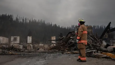 Reuters Firefighter at remains of Maligne Lodge, Jasper