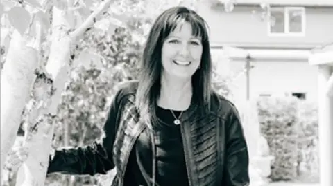 A black and white image of a woman in a black leather jacket, with long dark hair