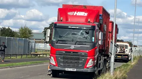 A red lorry which says 'Hills'