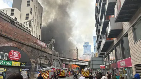 Three fire engines in the centre of Manchester as fire fighters tackle a huge fire sending plumes of smoke across the city. 