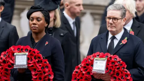 Getty Images Badenoch and Starmer stand opposite the cenotaph in black clothing with wreaths