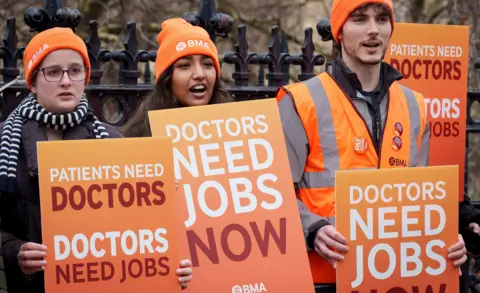 Richard Baker / In Pictures via Getty Images BMA resident doctors hold placards reading 'doctors need jobs now' while striking in London in December