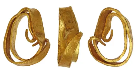 A bent gold torc photographed from three angles against a white background.