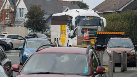 Roadworks causing huge traffic disruption. A coach completely blocks the road and is unable to turn round.