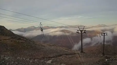 Winterhighland The ski tows and cables are free of ice and the snow has disappeared from the rocky ground below and the mountains beyond.