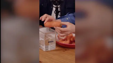 A carrot being held above a container of water