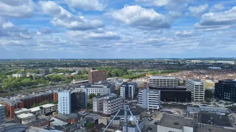 LDRS Birds-eye view of Swindon's centre, railway line and trees in the background. Lots of high-up buildings.