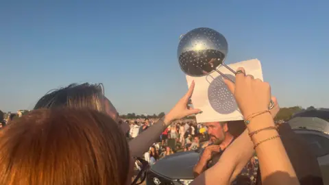 A woman is holding a colander up against a white piece of paper