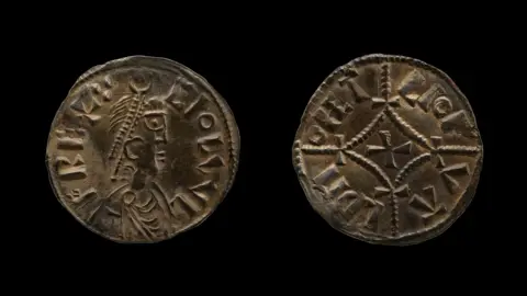 British Museum Undated handout photo issued by the British Museum of two ancient metal coins with an emperor on one coin and a cross in the middle of the other. They are on a black background.