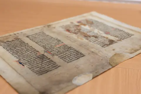 Max Rhydwen-Jones/States of Guernsey An old sheet of paper with written text, covered in stains and marks sits on a table.