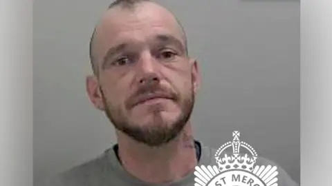 West Mercia Police Mugshot of Luke Simon wearing a grey jumper. He has short hair and a stubble