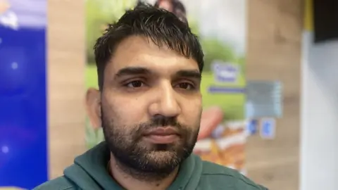 Sandeep Kumar, with brown hair and beard, wearing green top.