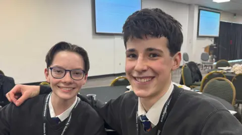 Two boys sat in a conference centre