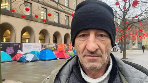 Mimicia Titianu wearing a black hat, white jumper and grey jacket in St Peters Square.