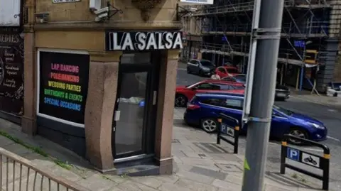 Street view of La Salsa lapdancing club on the corner of two streets. The street on the left of the image is 'Cow Green'. The sign in the window reads 'Lap Dancing, Poledancing, Wedding Parties, Birthdays & Events, Special Occasions'.
