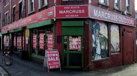 The exterior of Marcruss on Hotwell Road in Bristol. The shop windows are covered in 'closing down sale' signs.