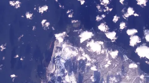 Planet Labs A satellite image of a coastline which is surrounded by vessels. 