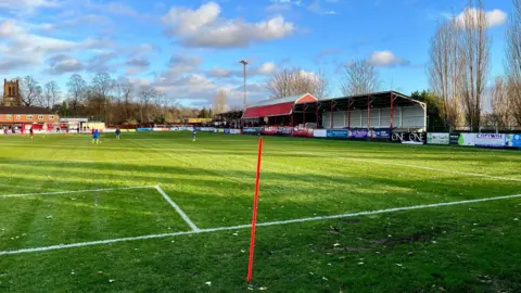 A football pitch with three stands on the right of the picture