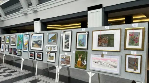 Linda Quirk An array of art, including a painting of a tiger, and a painting of a purple flower.