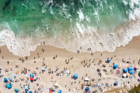 Kevin Carter/Getty Images  In an aerial view, people celebrate the Fourth of July along the coast of La Jolla's Windansea Beach on a warm summer day on July 4, 2023 in San Diego, California