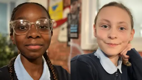 Simi on one side and Willow is on the other. Both are girls in school uniforms looking at the camera.