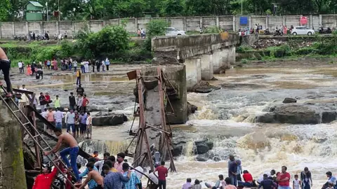 People gather near the site of a bridge collapse at Indrayani river near Kundamala village 
