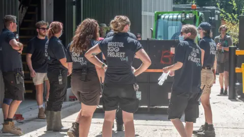Bristol Zoo Project/PA Bristol Zoo Project workers surround a black box on a green forklift truck containing the silverback gorilla.