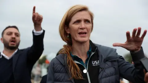 Reuters Mantan Badan Administrator Pembangunan Internasional (USAID) Samantha Power berbicara kepada media ketika ia mengunjungi pusat bantuan pengungsi dari wilayah Nagorno-Karabakh di desa perbatasan Kornidzor, Armenia. Dia mengenakan mantel gelap dan Bantuan Bantuan AS. 