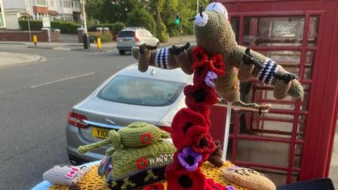 A crochet model of a Lancaster bomber and a tank on a post-box