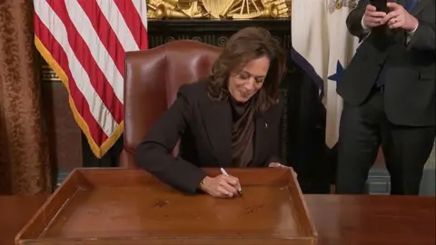 Harris signing her table  and smiling