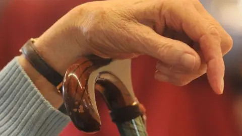 BBC Elderly lady's hand on walking stick