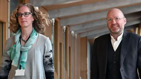 Lorna Slater and Patrick Harvie walking in the Scottish Parliament building 