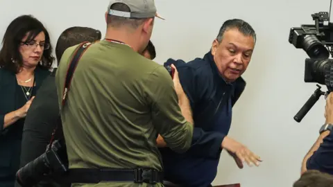 US Senator Alex Padilla, Democrat from California, is removed from the room after interrupting a news conference.