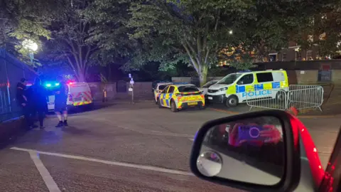 PA Media Police officers, vans and cars idle outside the Birmingham stadium.