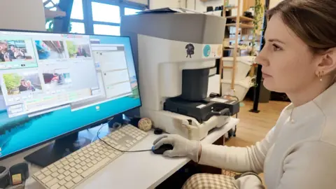 A women in white looks a a computer screen full of different images.