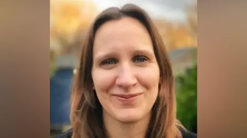 Dr Sarah Harvey Dr Sarah Harvey, a woman with brown hair, is seen against a blurred brown and green background. She is smiling while looking directly at the camera.