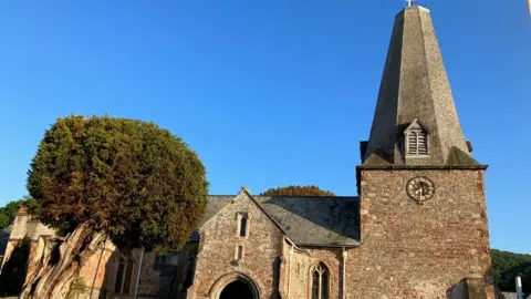 A 13th century church amde from red brick. The sky behind it is blue.