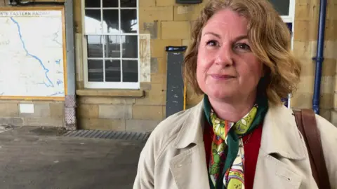 BBC/Seb Cheer A woman, Gemma, stands in Scarborough station and looks towards the camera.