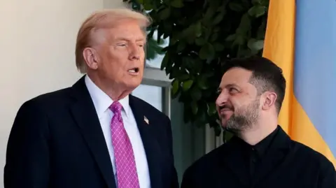 Reuters Donald Trump, wearing a white short and chequered violet and white tie speaks as Volodymyr Zelensky all in black looks up to him smiling