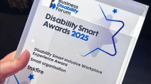 Inkfire Close-up of the award. A white rectangle bearing the words Disability Smart Awards 2025 and the name of the award and company - Inkfire.
