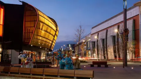 Elwick Place. A bubble shaped building lit up at night with benches and floor lights.