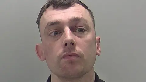 A police mug shot of Michael Hardy. He is wearing a dark coloured shirt. 