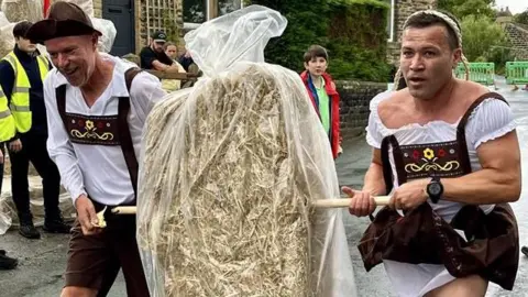 BBC/Dave Edwards Two people dressed in a costume giving the appearance of a Lederhose and Dirndl - traditional clothing often worn in German-speaking countries.