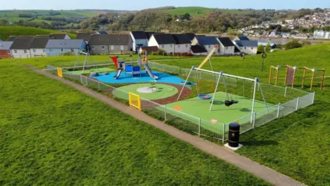 An ariel view of the East-the-water in Pollyfield play park. It has fresh equipement including two swings and a climbing frame with a slide.