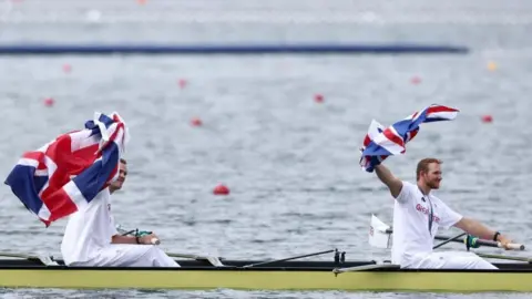 Reuters James Rudkin and Charles Elwes holding flags in a boat