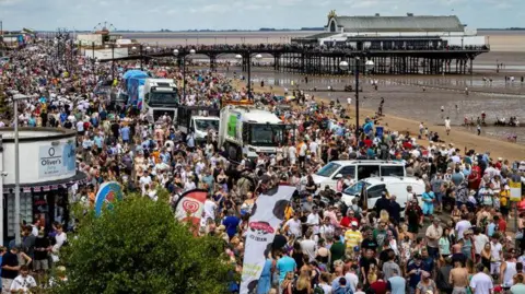 A wide view of the large crowds thronging the sea front.  Cleethorpes pier stretches out into the sea.