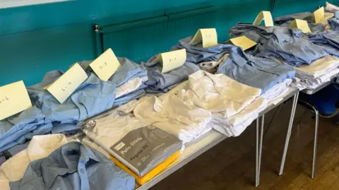 Piles of new and donated uniforms arranged in order of age
